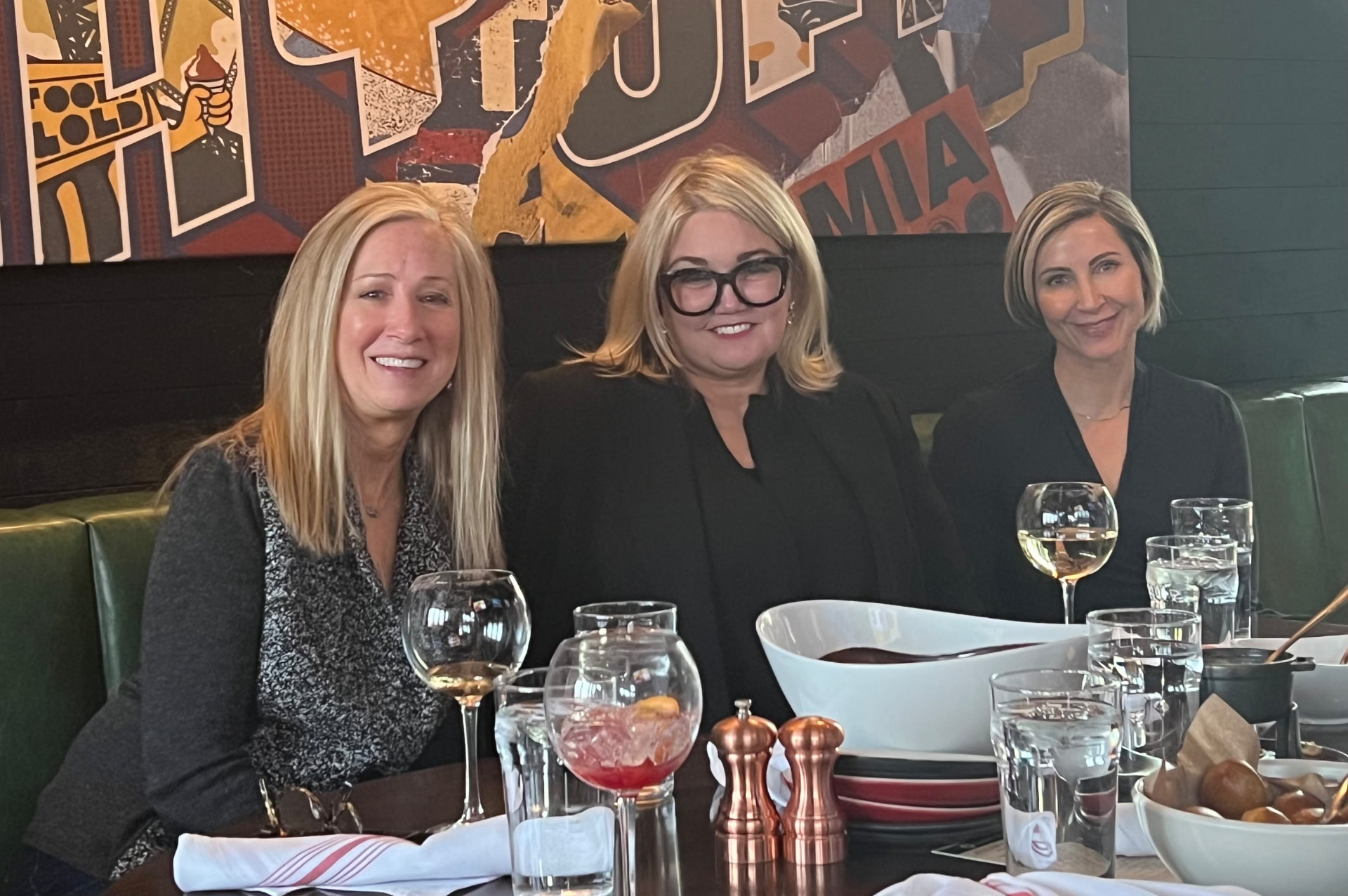 Three roundtable members smiling together over dinner